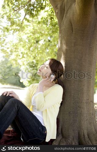 Japanese young woman listening to the music in the park