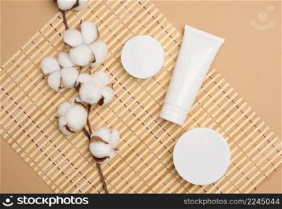 jar and empty white plastic tubes for cosmetics on a beige background. Packaging for cream, gel, serum, advertising and product promotion, mock up, top view