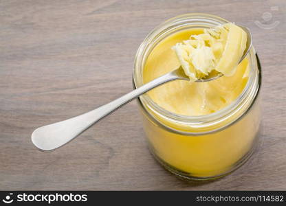 jar and tablespoon of ghee (clarified butter) on grained wood