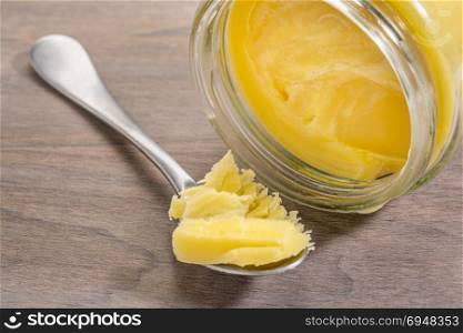 jar and tablespoon of ghee (clarified butter) on grunge wood