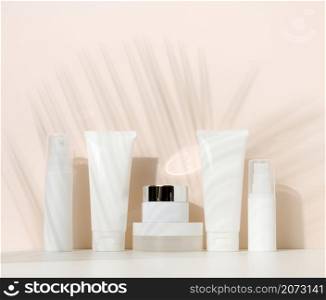 jar, bottle and empty white plastic tubes for cosmetics on a beige background. Packaging for cream, gel, serum, advertising and product promotion, mock up