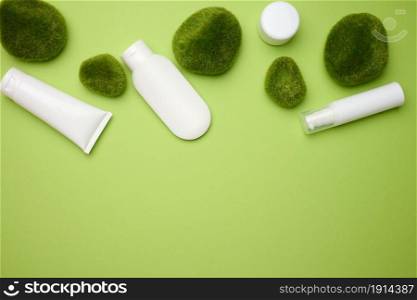 jar, bottle and empty white plastic tubes for cosmetics on a green background. Packaging for cream, gel, serum, advertising and product promotion, mock up
