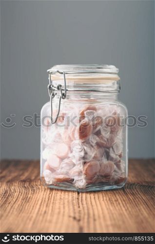 Jar filled with caramel milky candies on table