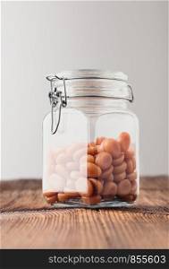 Jar filled with caramel milky candies on wooden table