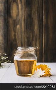 jar honey with beautiful flowers wooden surface