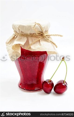 Jar of homemade cherry jam and couple of cherries