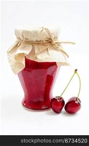 Jar of homemade cherry jam and couple of cherries
