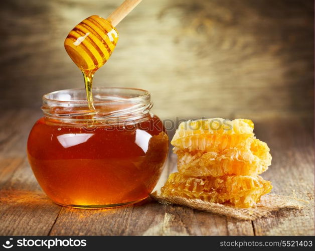 jar of honey with honeycomb on wooden table