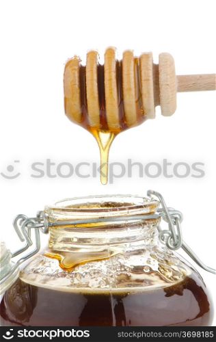 Jar of honey with wooden drizzler isolated on white background