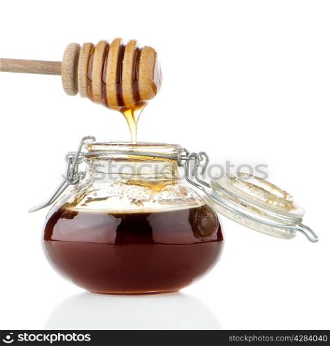 Jar of honey with wooden drizzler isolated on white background