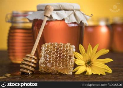 Jar of liquid honey. Sweet honey in the comb, glass jar on wooden background