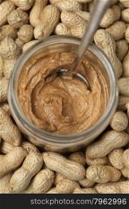 Jar of peanut butter among peanuts