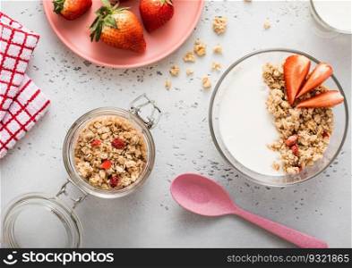 Jar of strawberry granola, plate with yogurt and glass of milk. Top view.