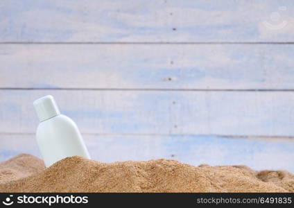 Jar of sunscreen on the beach sand.