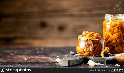 Jar with marinated mushrooms on the table. On a wooden background. High quality photo. Jar with marinated mushrooms on the table.