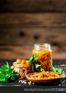 Jar with marinated mushrooms on the table. On a wooden background. High quality photo. Jar with marinated mushrooms on the table.