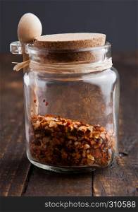 Jar with spices and small spoon on wooden board. Various spices
