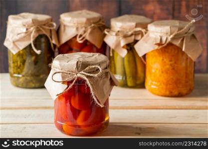 Jars of fermented vegetables on a wooden background. Home made canned cucumbers, tomatoes and sauerkraut.. Jars of fermented vegetables on wooden background. Home made canned cucumbers, tomatoes and sauerkraut.