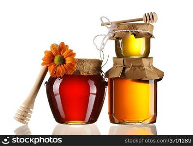 Jars of honey and dipper isolated over white
