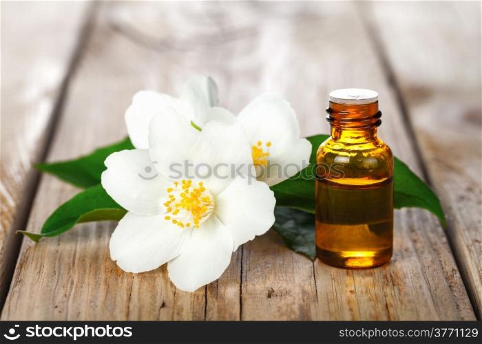 Jasmine essential oil and flowers on wooden table background. Beauty treatment