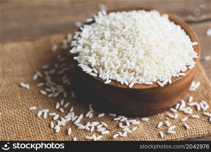 Jasmine white rice in wooden bowl and harvested rice on sack, harvest rice and food grains cooking concept