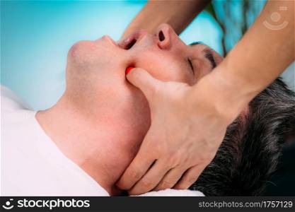 Jaw realignment massage treatment, a male client. Jaw Massage. Therapist Doing Realignment Massage, Male Client
