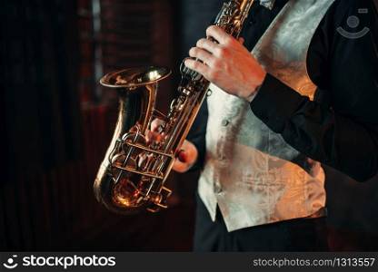 Jazz man hands holding saxophone closeup. Brass band musical instrument. Solo jazz-man with sax in studio. Jazz man hands holding saxophone closeup
