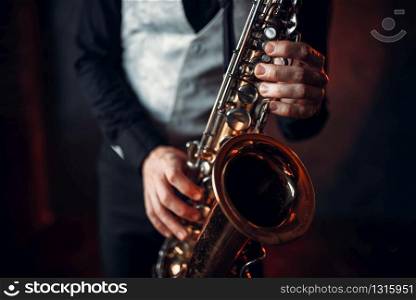 Jazz man hands holding saxophone closeup. Brass band musical instrument. Solo jazz-man with sax in studio