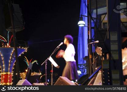 Jazz singer on outdoor stage clapping hand, motion blur my long exposure