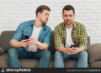 jealous boyfriend spying his male friend watching his phone