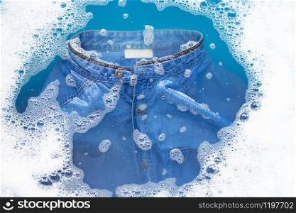 Jean shirt soak in powder detergent water dissolution. Laundry concept