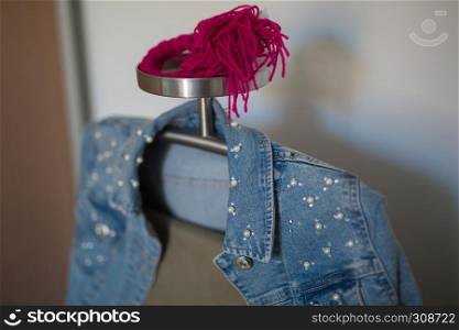 Jeans Jacket with White Beads and Beige Trousers Hanging on a Metal Coat Rack.. Jeans Jacket with White Beads and Beige Trousers Hanging on a Metal Coat Rack