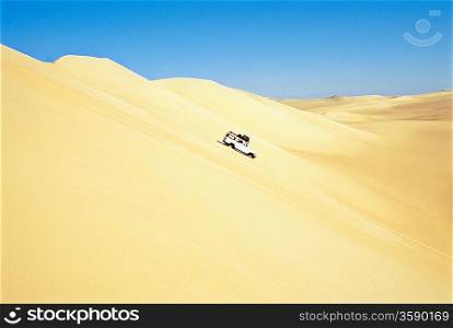 Jeep driving down sand dune