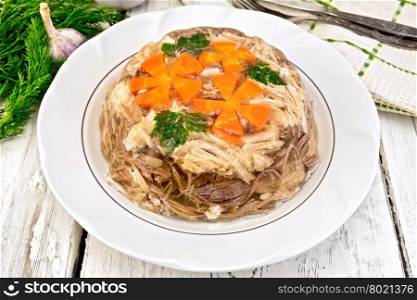 Jellied pork and beef with carrots and parsley on a plate, tea towel, garlic and dill on a wooden boards background