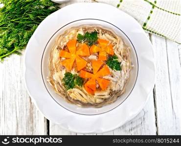 Jellied pork and beef with carrots and parsley on a plate, towel, garlic, mustard and dill on the background of wooden boards on top