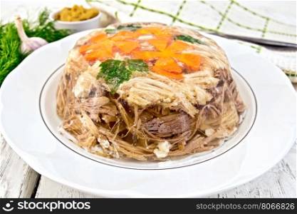 Jellied pork and beef with carrots and parsley on a plate, towel, garlic, mustard and dill on the background light wooden boards