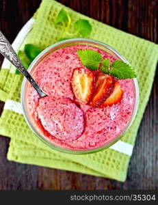 Jelly air strawberry in a glass bowl with a spoon, mint on a green towel on a background of wooden boards on top