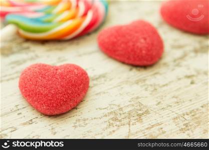 Jelly beans hearts with a colorful lollipop on a wooden background. Focus in the foreground