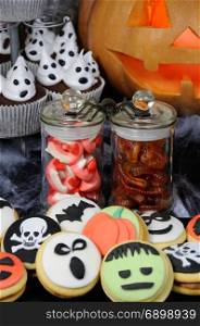 Jelly candies in the form of jaws and worms in a jar on a Halloween table among other sweets