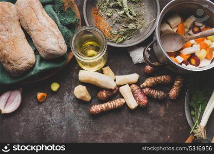 Jerusalem artichoke cooking preparation on rustic kitchen table with pot, diced vegetables, oil and ingredients, top view