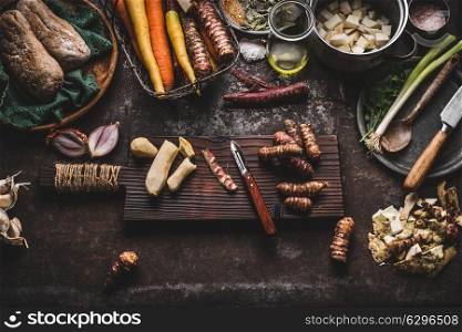 Jerusalem artichoke peeling preparation on rustic kitchen table with pot, diced vegetables, oil and ingredients, top view. Healthy and clean seasonal food cooking and eating concept
