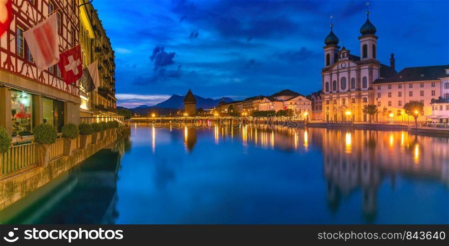 Jesuit Church, Water Tower, Wasserturm, and traditional frescoed building along the river Reuss at night in Old Town of Lucerne, Switzerland. Lucerne at night, Switzerland