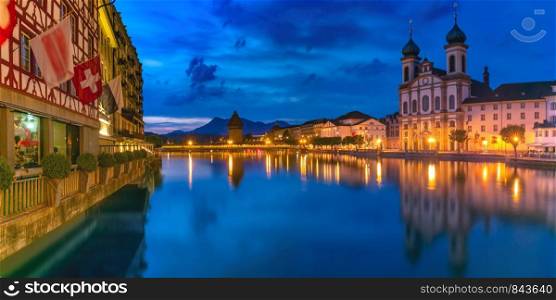 Jesuit Church, Water Tower, Wasserturm, and traditional frescoed building along the river Reuss at night in Old Town of Lucerne, Switzerland. Lucerne at night, Switzerland