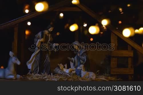 Jesus Christ Nativity scene with atmospheric lights. Jesus Christ birth in a stable with Mary and Joseph figures. Christmas scene.