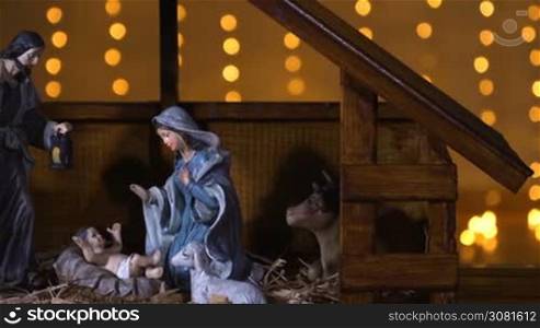 Jesus Christ Nativity scene with atmospheric lights. Jesus Christ birth in a stable with Mary and Joseph figures. Christmas scene. Dolly shot