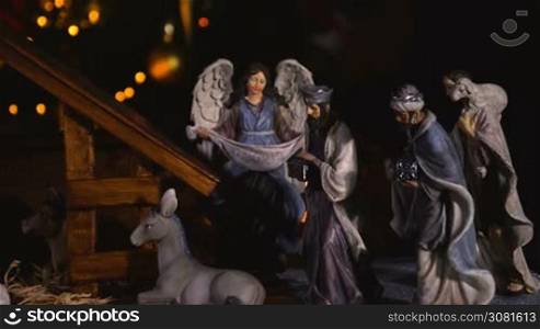 Jesus Christ Nativity scene with atmospheric lights. Jesus Christ birth in a stable with Mary and Joseph figures. Christmas scene. Dolly shot