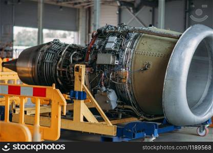 Jet airplane turbine on repairing in hangar, plane engine without covers on maintenance, nobody. Air transportation safety concept. Jet airplane turbine on repairing in hangar