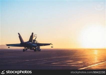 Jet fighter on an aircraft carrier deck against beautiful sunset sky . Elements of this image furnished by NASA. NASA F/A-18 Towed At Sunrise for Flight