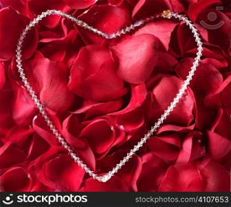Jewel necklace over bed of red rose petals