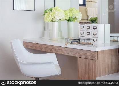 Jewelry accessory and jar of flower on white top dressing table